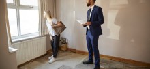 Female First Time Buyer Looking At House Survey With Realtor