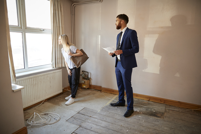 Female First Time Buyer Looking At House Survey With Realtor